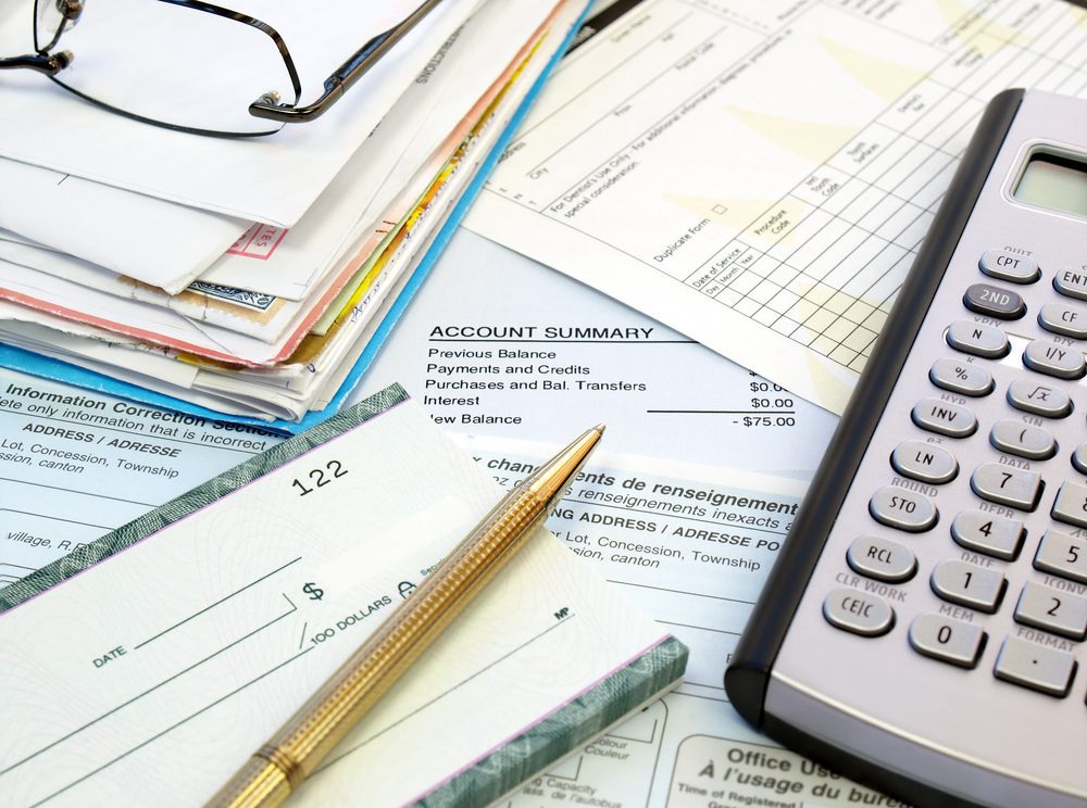 bills, a calculator, and a checkbook to pay bills