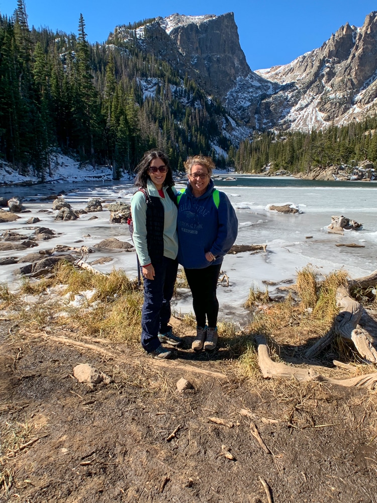 My mom and I at Rocky National Park, mountains and a frozen lake in the background