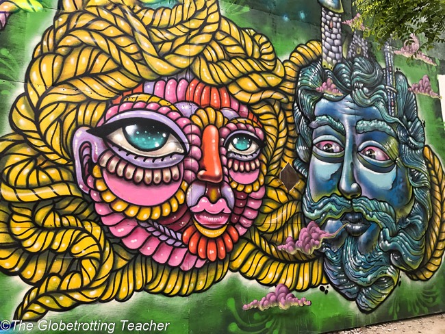 NYC street art - a mural with 2 faces, one painted blue and the other pink and purple with golden braid hair.