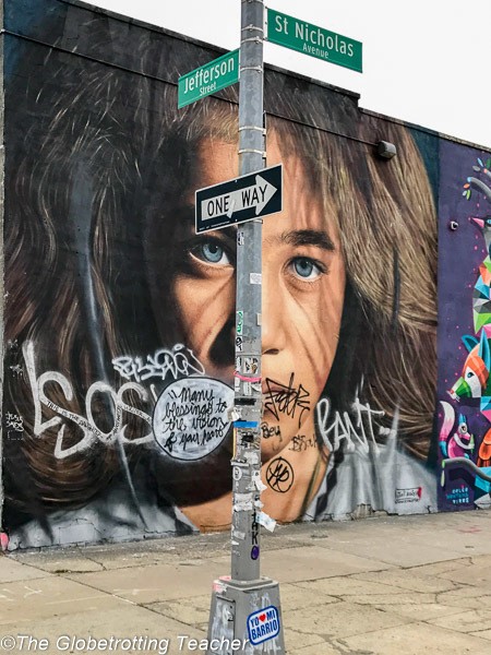 Street art in NYC - A boy's face with long brown hair and blue eyes so life-like it seems like a photograph