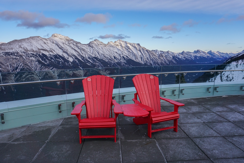 Red chairs on the viewing platform at the Banff Gondola. Mountains in the background