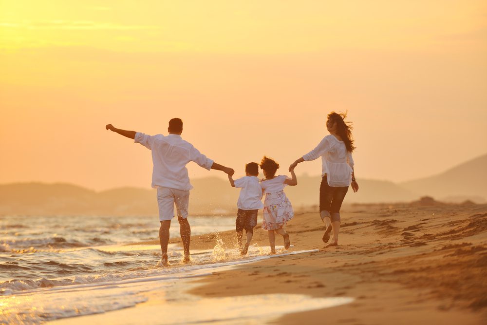 Happy young family have fun on beach run and jump at sunset