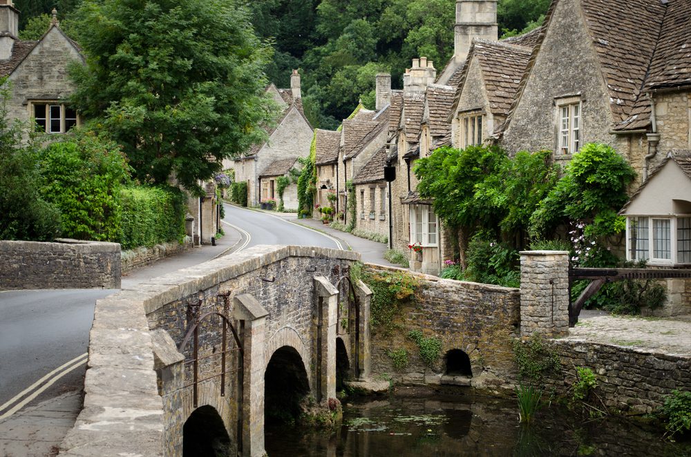 English countryside village street with a bridge over a stream into an area with stone cottages