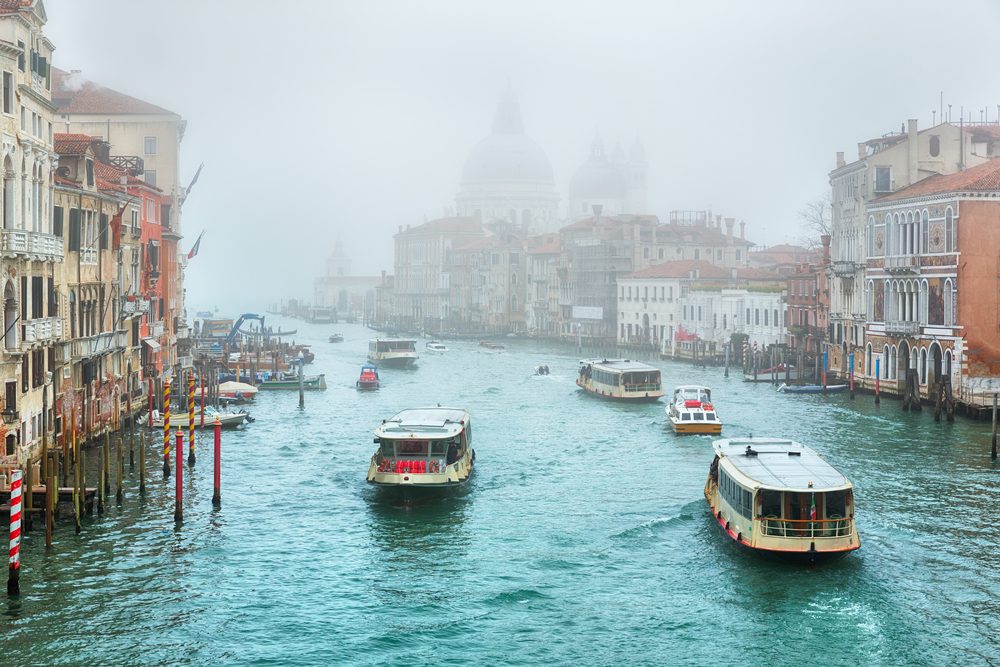 Foggy (misty) Venice. Canal (channel), historical, old houses and boats in thick fog. Scenic cityscape view. Venice, Italy