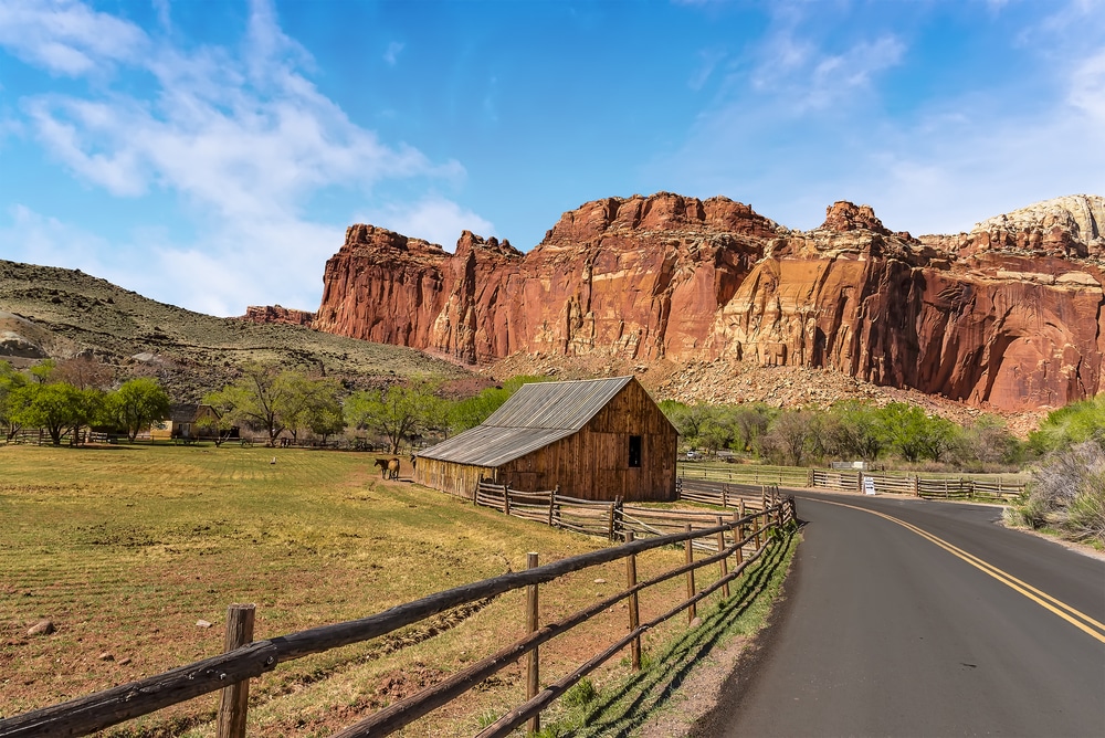 road with mountains and a barn in Capitol Reef National Park in Utah