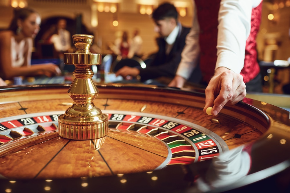 Hand of a croupier with a ball on a roulette wheel during a game in a casino. Gambling betting game poker roulette casino concept.