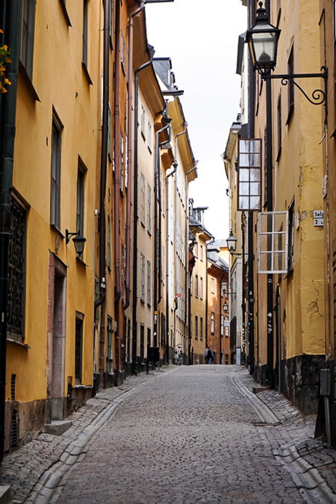 Street in Gamla Stan in Stockholm, historic yellow buildings on either side of the cobblestone street