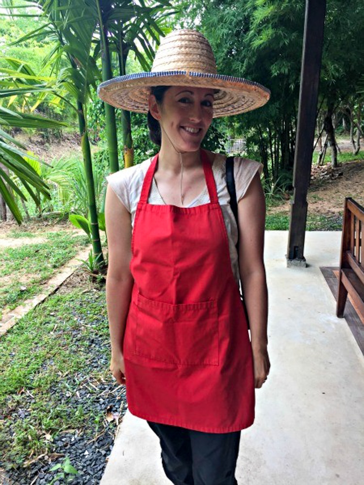 Me in a red apron and straw hat at my cooking class in Chiang Mai Thailand