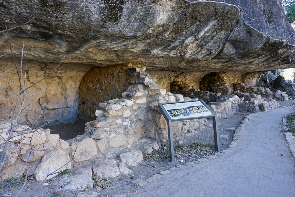 cave dwelling with an information sign in front at Walnut Canyon National Monument