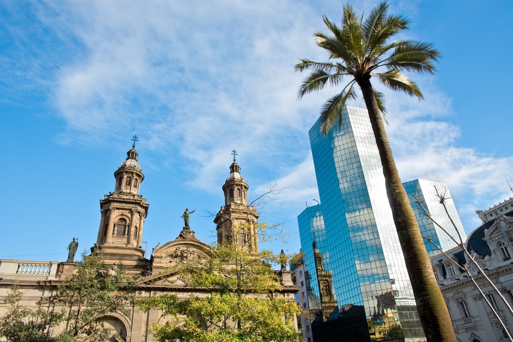 The Cathedral of Santiago de Chile in Plaza de Armas. - Neoclassical church with a modern skyscraper and a palm tree