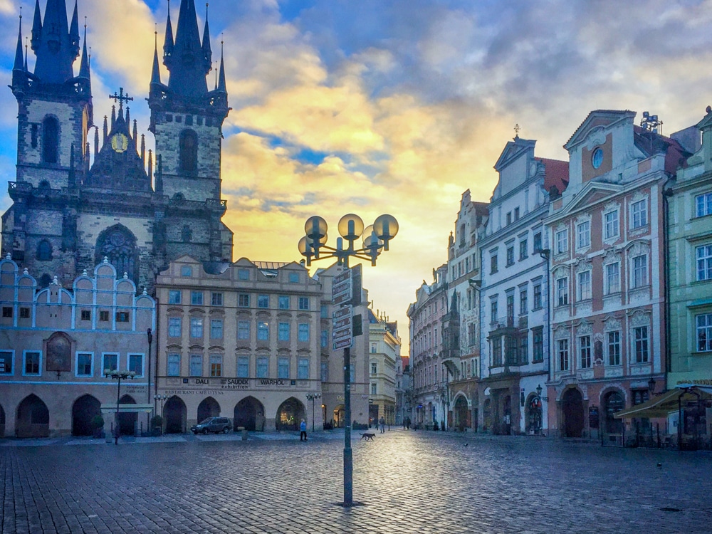 Old Town Square at sunrise in Prague Czech Republic - Gothic church facade with colorful historic buildings in an empty square