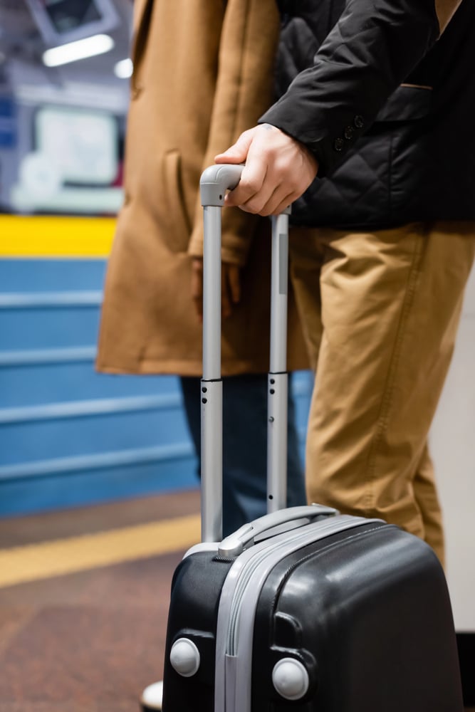 closeup view of people standing with a suitcase on a subway platform