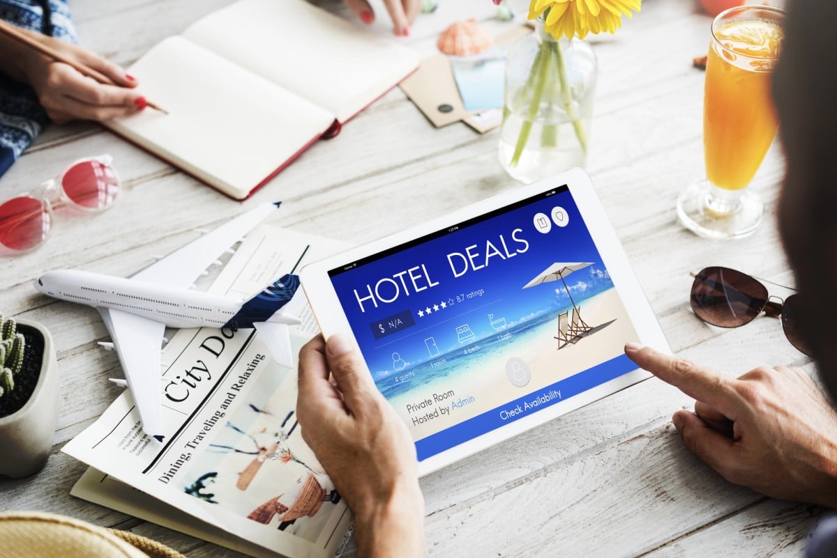 travel deals on an ipad with someone touching the screen
